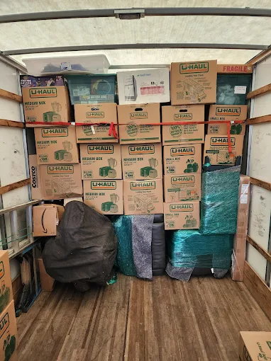 A fully loaded moving truck packed floor to ceiling with labeled boxes and wrapped items.